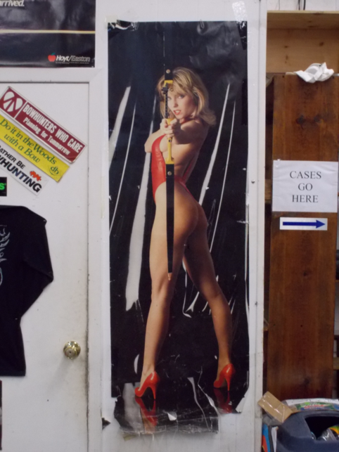 Female model in high heels and red bathing suit shooting recurve bow. Located on closet.