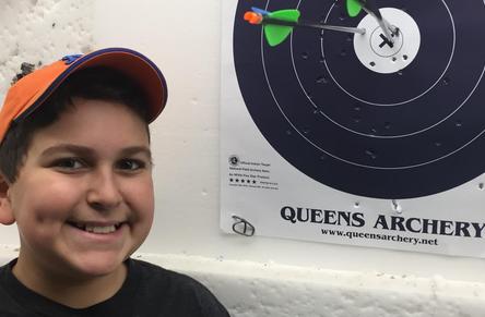 Smiling male child next to target with arrow in bullseye